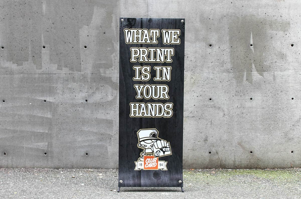 24 by 60 inch portable X-frame banner stand displayed outdoors against a concrete wall background