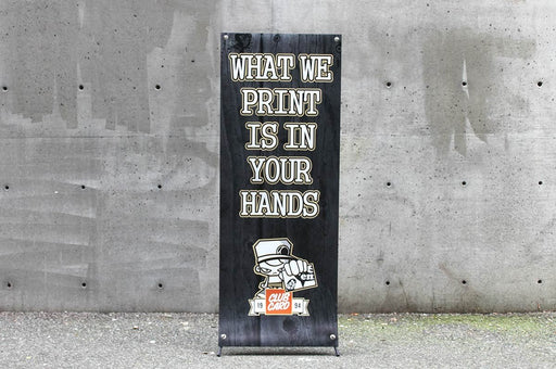 24 by 60 inch portable X-frame banner stand displayed outdoors against a concrete wall background