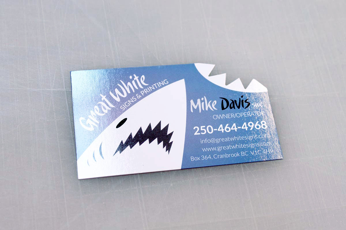 Custom shape die cut business card for Great White Signs & Printing on our Silk Laminated 16pt Stock | There is a great white shark in the bottom left corner, with the top right corner die cut to look like the shark bit it | Clubcard Printing USA