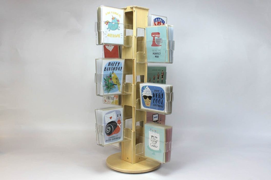 Birch plywood countertop card spinner with 12 clear acrylic pockets holding various types of greeting cards.