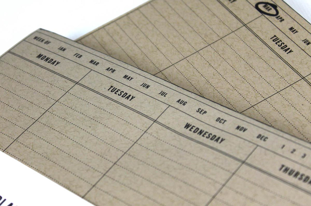 Close up of a stack of of two natural kraft weekly planner notepads.
